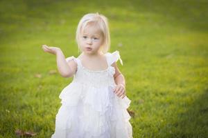 aanbiddelijk weinig meisje vervelend wit jurk in een gras veld- foto