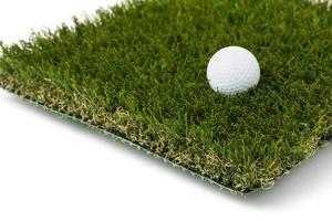 golf bal resting Aan sectie van kunstmatig grasmat gras Aan wit achtergrond