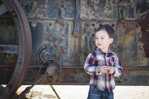 schattig jong gemengd ras jongen hebben pret in de buurt antiek machinerie foto