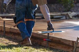 bouw arbeider gladmaken nat cement met troffel gereedschap foto