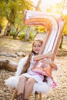schattig jong meisje spelen met aantal zeven mylar ballon buitenshuis foto