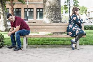 ongelukkig gemengd ras paar zittend geconfronteerd weg van elk andere Aan park bank foto