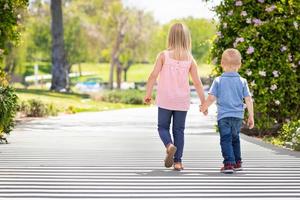 jong zus en broer Holding handen en wandelen Bij de park foto
