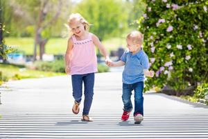 jong zus en broer Holding handen en rennen Bij de park foto