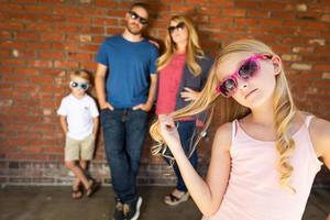 schattig jong Kaukasisch meisje vervelend zonnebril met familie achter foto