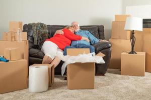 aanhankelijk moe senior volwassen paar resting Aan bankstel omringd door in beweging dozen foto