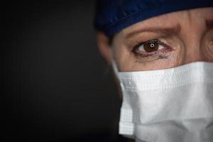 betraand benadrukt vrouw dokter of verpleegster vervelend medisch gezicht masker Aan donker achtergrond foto