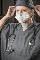 vrouw dokter of verpleegster met stethoscoop zetten Aan beschermend gezicht masker foto