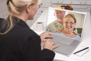 vrouw in keuken gebruik makend van laptop - online met senior paar foto