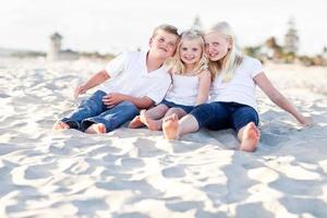 aanbiddelijk zussen en broer hebben pret Bij de strand foto