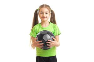 schattig weinig meisje in groen overhemd Holding een voetbal bal in handen foto