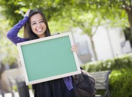 opgewonden gemengd ras vrouw leerling Holding blanco schoolbord foto