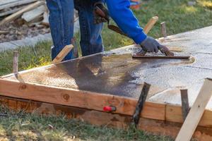 bouw arbeider gladmaken nat cement met troffel gereedschap foto