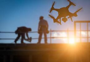 silhouet van onbemande vliegtuig systeem quadcopter dar in de lucht over- gebouw onder bouw. foto