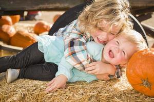 weinig jongen spelen met zijn baby zus Bij pompoen lap foto