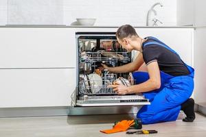 jong mannetje technicus controle vaatwasser met digitaal multimeter in keuken foto