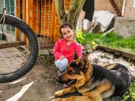 weinig meisje met een Duitse herder in de werf foto