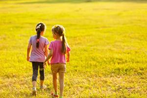 twee weinig meisjes wandelen in de veld. foto