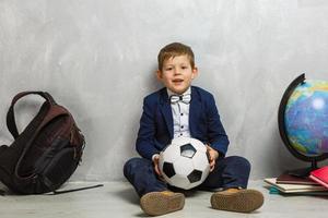 gelukkig schattig knap jongen in bril met school- zak en boek. modern rugzak. kind is klaar naar antwoord op een achtergrond. eerste tijd naar school. terug naar school- foto