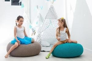 twee gelukkig weinig meisjes zijn glimlachen terwijl spelen in kinderen kamer Bij huis foto