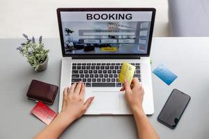 vrouw Holding credit kaart en computer met app hotel reservering scherm foto