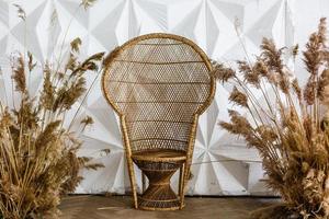 Pauw rieten stoel in een ruim slaapkamer interieur. rotan Pauw fauteuil door de wit leeg muur in de leven kamer. Scandinavisch stijl huis. rustiek kamer interieur. eco meubilair, natuurlijk meubilair foto