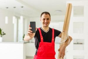 appartement klusjesman houdt een smartphone in zijn hand- foto