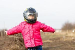 portret van een weinig meisje glimlachen in een beschermend helm vrouw kind in motorcross moto helm. fietser meisje in motorcross helm foto