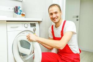 het wassen machine reparatie. reparateur handen met schroevedraaier demontage beschadigd eenheid voor reparatie foto