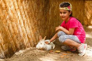 de kind feeds konijnen in de kinderboerderij dierentuin foto