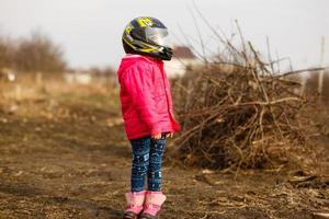 portret van een weinig meisje glimlachen in een beschermend helm vrouw kind in motorcross moto helm. fietser meisje in motorcross helm foto