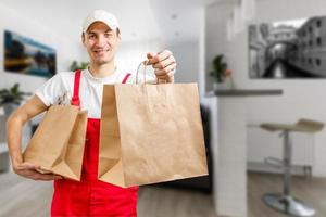 levering, mail en mensen concept - gelukkig Mens leveren voedsel in beschikbaar papier zak naar klant huis foto