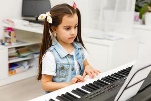 schattig weinig meisje Toneelstukken Aan piano, synthesizer. opleiding. onderwijs. school. esthetisch opleiding. elementair klas. foto