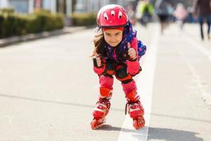 grappig weinig mooi meisje Aan rol skates in helm rijden in een park. gezond levensstijl concept foto
