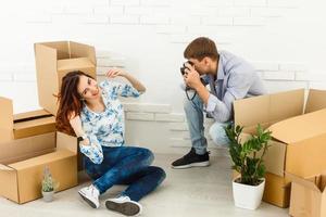 glimlachen paar leunend Aan dozen in nieuw huis foto