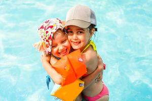 twee weinig kinderen spelen in de zwemmen zwembad foto