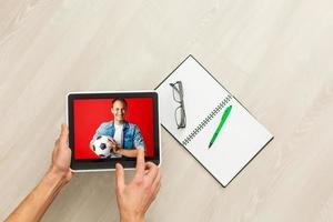 hand- Holding tablet met voetbal bal vliegend uit scherm foto