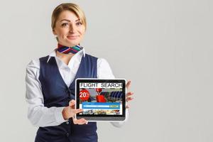 charmant stewardess gekleed in blauw uniform met tablet vlucht foto