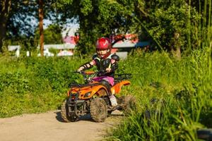 weinig meisje rijden atv quad fiets in ras bijhouden foto