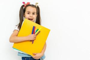portret van glimlachen school- meisje kind met rugzak en boeken geïsoleerd Aan een wit achtergrond foto