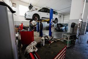 twee monteur in onderhoud reparatie station werken met auto in tillen. foto