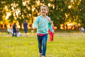 twee zussen rennen Aan de gazon in de stad park buitenshuis. vrijheid en zorgeloos. gelukkig kinderjaren foto