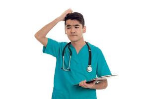 jong Mens dokter poseren in uniform met stethoscoop en kladblok geïsoleerd Aan wit achtergrond in studio foto