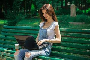 schattig brunette meisje werken met laptop buitenshuis foto