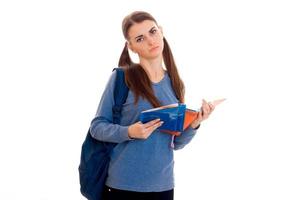 een tiener- meisje met reusachtig houdt Aan schouder rugzak en een map in de handen foto