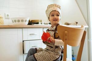 portret van schattig weinig thuiskok meisje in wit keuken. foto