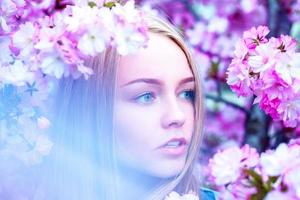 horizontaal portret van aanbiddelijk jong blond in bloeiend bloemen foto