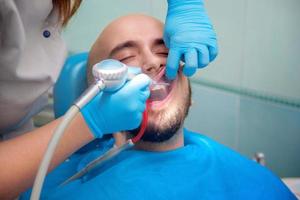 Mens behandelt zijn tanden Bij de tandarts foto
