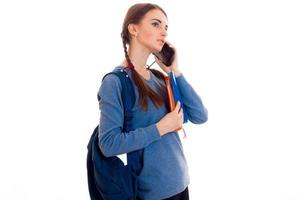 jong meisje in blauw jasje Holding een aktentas en zei door mobiel telefoon foto