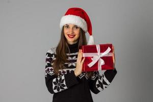 vrouw in warm trui en de kerstman hoed met rood geschenk foto